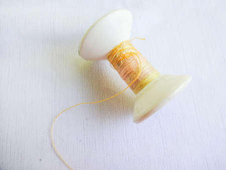 Spool of yellow orange thread isolated on white background.の写真素材