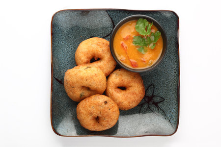 South indian food, breakfast- MeduVadai served in a ceramic plate with sambar