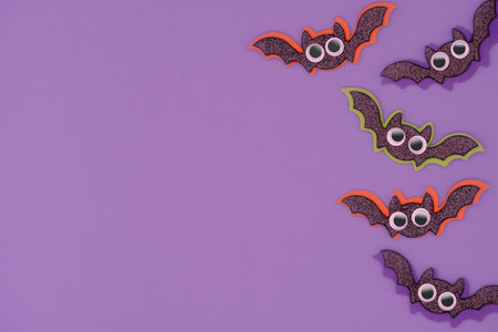 Halloween background with copy space. Cute glistering bats with big eyes on purple backdrop.の写真素材