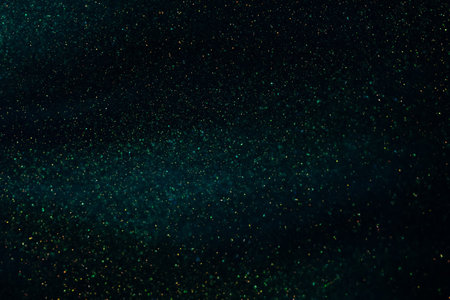 Countless vortex of gold particles in dark blue-green liquid. Golden glittering sparkling particles in green fluid. Magical dark galaxy with gold dust glistening.の写真素材