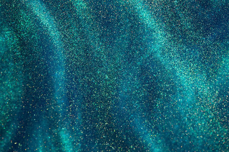 Gold dust particles and sparkling bokeh in a green liquid. Green fluid with golden overflow and glittering dispersion. Magic Galaxy Of Golden Particles Flows on Green Background.の写真素材