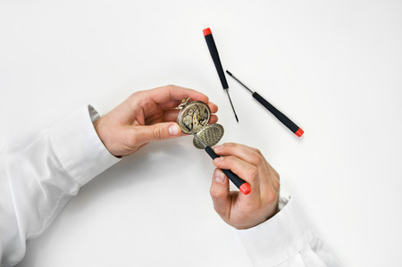 Watchmaker holding antique pocket watch show the clockwork mechanism and repair with screwdriver. の写真素材
