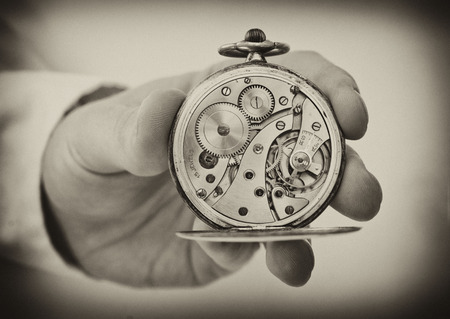 Vintage style image. Hand holding antique pocket watch show the clockwork mechanism.の写真素材