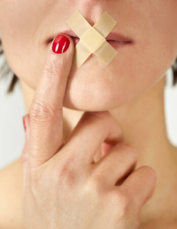 Sexy girl with an adhesive bandage and finger over her mouth