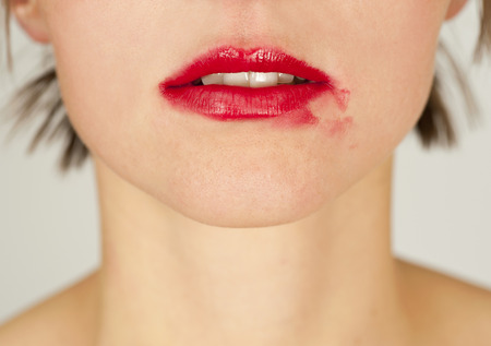 Girl face with red smeared lipstick on her lipsの写真素材