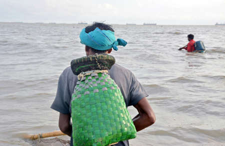 Two Fisherman catching fish in sea with net.の写真素材