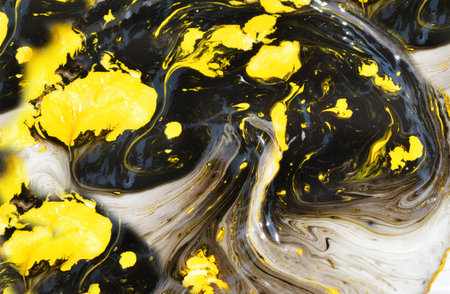 abstract background of yellow and black acrylic paint mixing in water on black backgroundの写真素材