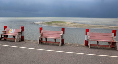 Bench on the beach with stormy sky and sea in background.