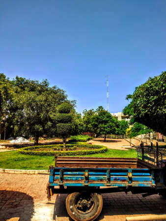A Blue Tractor with garden,trees and tower at the background with blue sky.This area is in my college.の写真素材