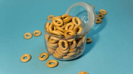 Yellow small sushki bagels in glassware on a blue background. Bagels are scattered around