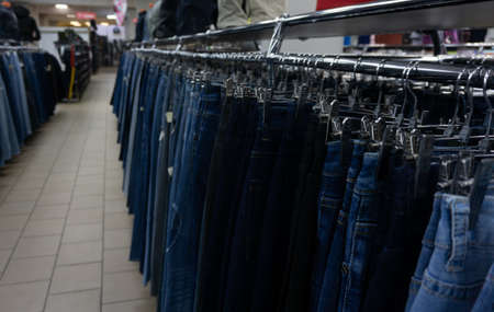 Jeans in the mall hang on hangers. Large selection of denim clothing
