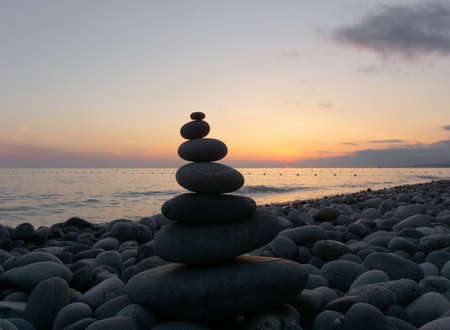 Stack of zen stones on the beach at sunset, beautiful seascape. Made of stone tower as rest balance...