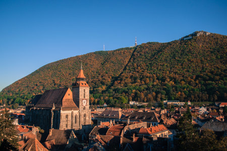 The Black Church, a stunning Gothic landmark in BraÈov, Romania, stands surrounded by vibrant autumn foliage and picturesque red rooftops. This medieval masterpiece, nestled in the heart of Transylvania, offers a breathtaking blend of history, culture, and scenic beauty, making it a must-visit destination for travelers.の写真素材