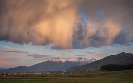 A captivating scene of storm clouds illuminated by the golden glow of sunset above the Bucegi...