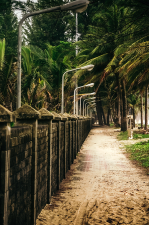 Pavement in sand running alongside of fence and beach of Kamala.の写真素材