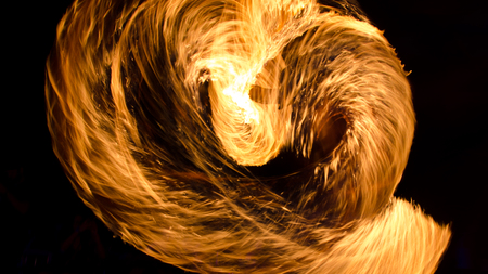 Anonymous man in flashes of fire on beach performing fire show,の写真素材