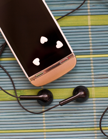 Touch screen phone with earphone set on the unique backing closeup simple compositionの写真素材