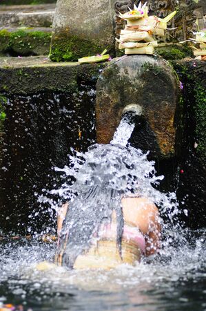 Woman bathing i  Tirta Empul water temple. Ubud Bali Indonesiaの写真素材