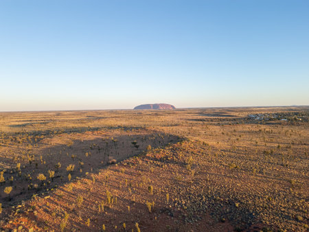 A breathtaking aerial view of Uluru Rock in Australia illuminated by a stunning sunsetの写真素材