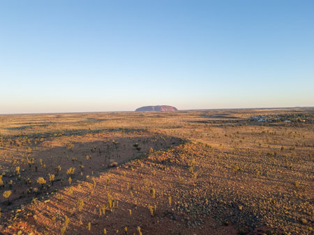 A breathtaking aerial view of Uluru Rock in Australia illuminated by a stunning sunsetの写真素材