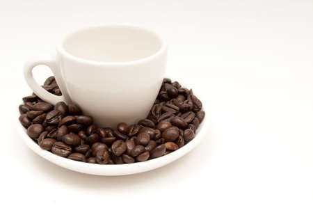 cup surrounded by coffee beans and isolated on a white background with copy space to the rightの写真素材