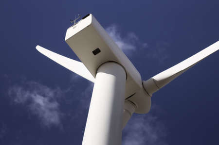 Wind turbine against a sky blue background with clouds.の写真素材