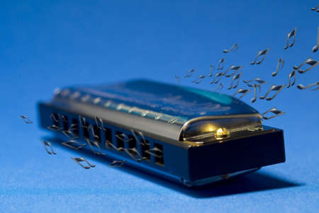 A photo of a harmonica and notes, on a blue backgroundの写真素材