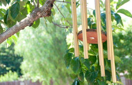 metal wind chimes swaying in the breeze under a treeの写真素材