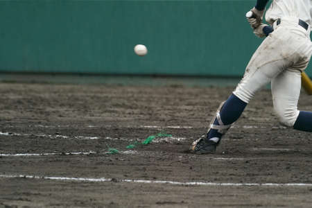 A batter at the moment of hitting a ball thrown by a pitcher during a baseball game.の写真素材