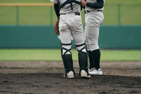 Pitcher and catcher gather on the mound during a baseball game.の写真素材