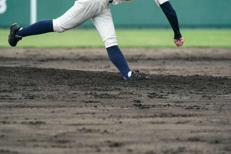 Pitcher throwing a white ball from the mound during a baseball game.の写真素材