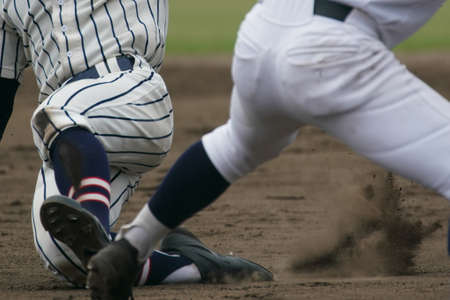 Baseball player sliding into a base while attempting to steal a base during a baseball game.の写真素材