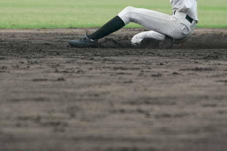 Baseball player attempting to steal a base during a baseball game.の写真素材