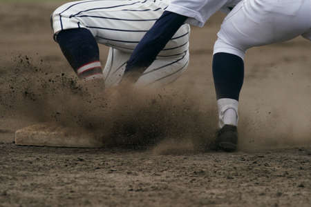 Baseball player sliding into a base while attempting to steal a base during a baseball game.