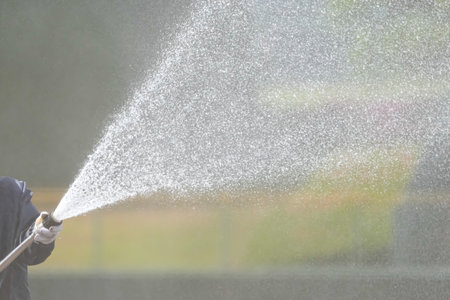 A maintenance worker sprinkles water on a baseball field and maintains it.の写真素材