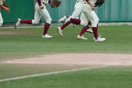 A baseball game is about to start and the players on the offensive team are dashing to the defense.の写真素材