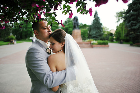Happy wedding couple on backqround red flowersの写真素材
