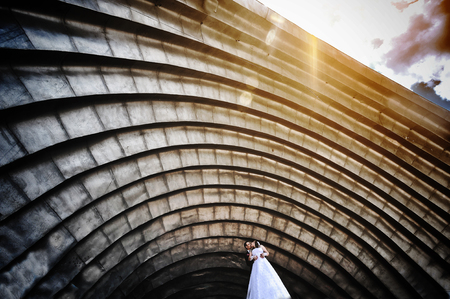 wedding couple under big arena hall arch on sunsetの写真素材