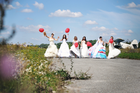 funny brides with balloons at the hand on the airportの写真素材
