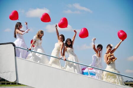 funny brides with balloons at the hand on the airportの写真素材