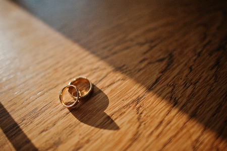two wedding rings in shadows on wooden tableの写真素材