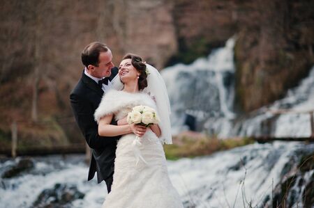 lovely newlyweds background waterfall at cold autumn dayの写真素材