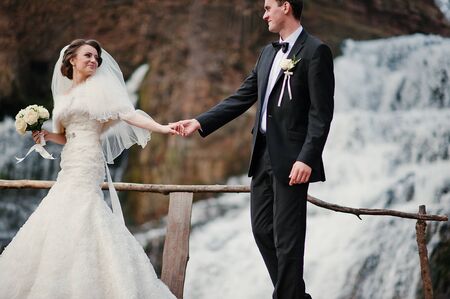 lovely newlyweds background waterfall at cold autumn dayの写真素材
