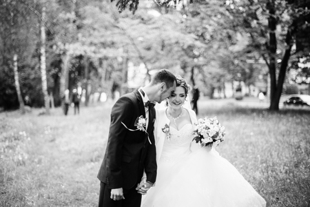 Young lovely and cheerfull wedding couple walking at the parkの写真素材