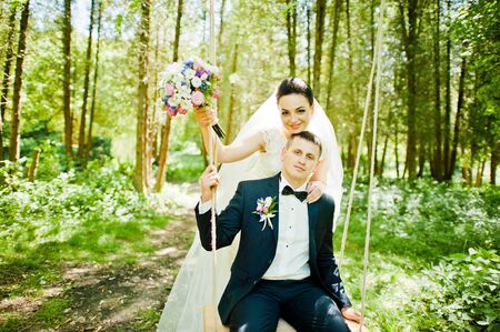 Newlyweds on swing on woodの写真素材