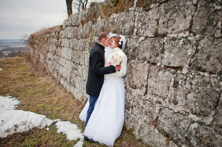 Young wedding couple on winter background stone landskape and wall of old castleの写真素材
