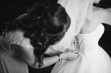Bridesmaid tying bride dressの写真素材