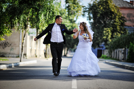 Wedding couple running and have fun on the roadの写真素材