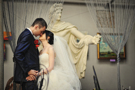 Kissing wedding couple near the monument of antique manの写真素材