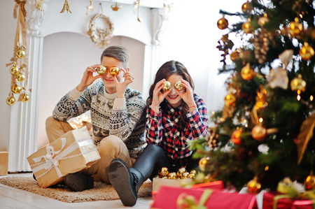 Young stylish couple with Christmas gifts and New Year decoration. Soft warm color tone.の写真素材